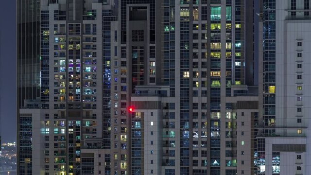 Lights from windows of offices and apartments aerial timelapse. Skyscrapers with working people in the evening in Business Bay, Dubai, United Arab Emirates. Complex of towers at night