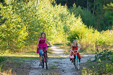 happy girls eating a bicycle at a distance from each other along a path in the forest, evening walk, self-isolation.