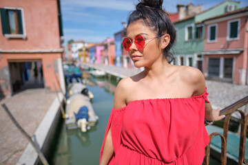 elegant, fashionable girl with glasse stay in the street , in a romantic Burano,Italy