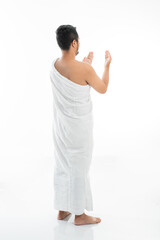 Muslim man praying while standing in white traditional clothes open his arm shoot from behind