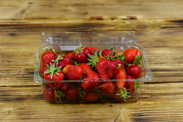 Fresh strawberry in plastic box on a wooden table