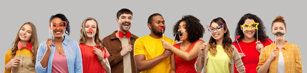 photo booth and fun concept - happy smiling people with party props over grey background