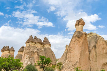 Fairy chimney rock formations shaped like mushrooms under a cloudy summer sky in Devrent Valley,...