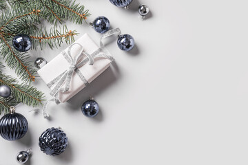 Christmas gift box with blue glass balls and fir branches. Space for text. Flat lay style.
