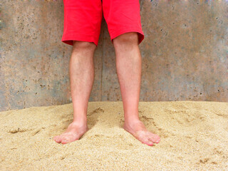 Male feet in the sand. Legs of a man in red shorts.
Male feet on the yellow sand of Ericeira beach,...