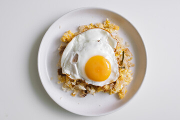 Homemade fried rice with fried egg on top served on white dish.