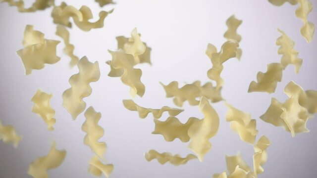 Pasta mafalde corte is flying up and rotating on a white background in slow motion