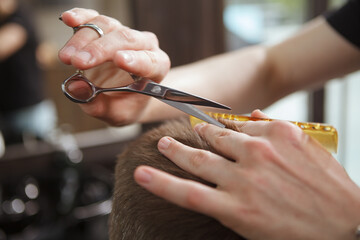 Close up of a barber using scissors at work, giving male client a new haircut