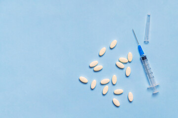 Syringe with pills on blue background with copy space