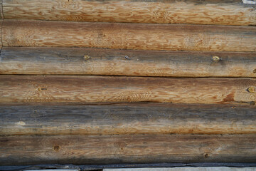 A wall made of natural wood of different sizes and shapes, Log house or barn, textured horizontal walls