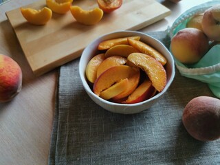 juicy sliced peaches in a plate, next to whole peaches in a reusable bag