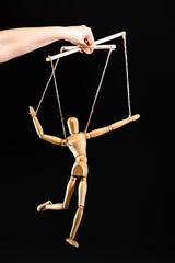 cropped view of puppeteer holding wooden marionette isolated on black
