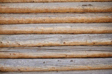 A wall made of natural wood of different sizes and shapes, Log house or barn, textured horizontal walls
