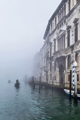 Foggy (misty) Venice. Canal (channel), historical, old houses and gondoliers with gondolas on thick fog.