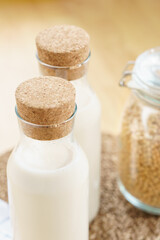 Two glass bottles of fresh and homemade soy milk with glass jar full of organic soybeans on wooden table. Alternative healthy milk, lactose intolerance drink, vegan and plant based diet concept. 