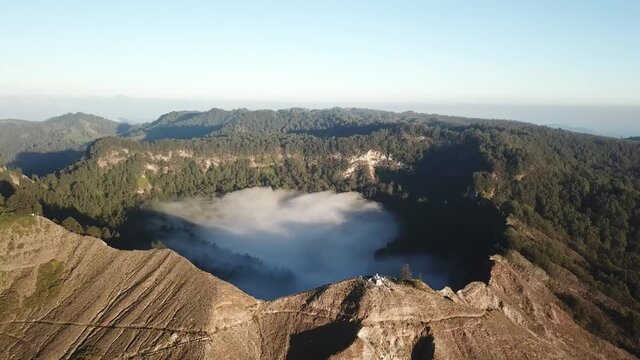 A drone capture of an early morning over the Kelimutu Lakes on Flores, Indonesia. The volcanic lakes are located in volcanic craters. One of the lakes is covered with fog. Golden hour. Calmness
