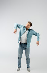 young man posing like puppet isolated on grey
