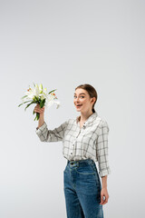 happy attractive girl posing like puppet with flowers isolated on grey