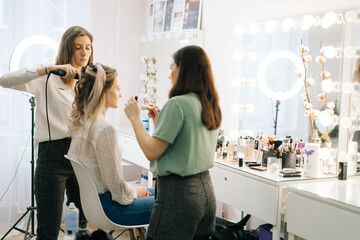 Portrait of two professional make-up artist doing makeover in lighting dressing room. Concept of...