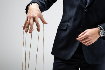 partial view of puppeteer in suit with strings on fingers isolated on grey