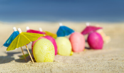 Texture (background) with colorful easter eggs with umbrellas on the beach with sky.