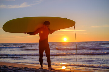 Positive surfer carrying surfboard during sunset