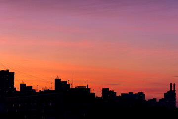 Obraz na płótnie Canvas Pink orange purple sunset over the city. Multicolored sky and black silhouette tall buildings of the metropolis