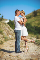 Stunning sensual outdoor portrait of young stylish fashion couple kissing in summer. Soft sunny colors.
