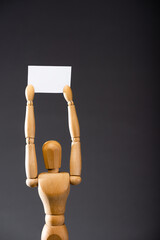 wooden marionette holding blank placard on black background