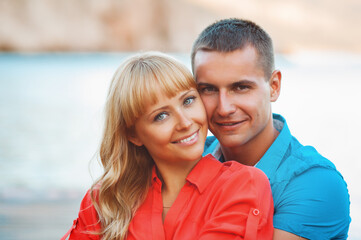 Fototapeta premium The happy young couple walking on a wooden pier on the seashore and are dressed in fashionable clothes. Having fun.