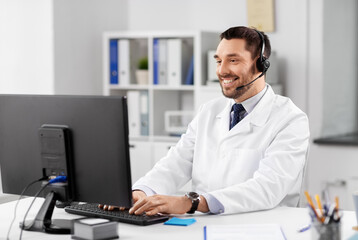 Fototapeta na wymiar healthcare, medicine and technology concept - happy smiling male doctor with computer and headset working at hospital
