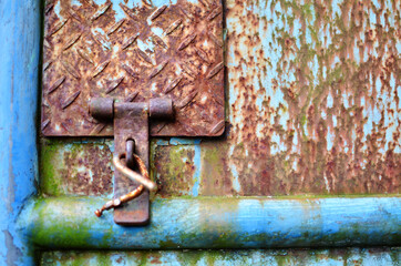 Gate latch on rusty metal door