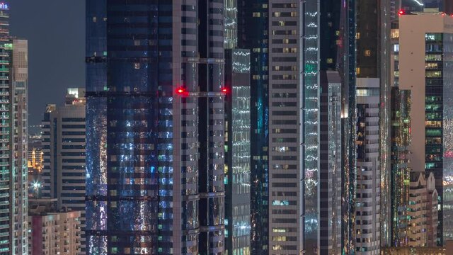 Dubai Financial Centre district with illuminated modern skyscrapers night timelapse. Aerial view from Downtown with lights from towers