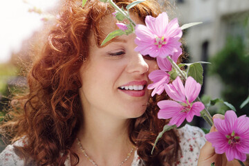 jeune et jolie jeune femme rousse caucasienne romantique aux longs cheveux bouclés souriant à...