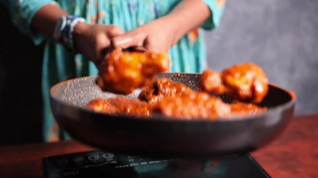 Closeup Of A Female Chef Tossing Crispy Fried Hot Buffalo Chicken Wings In A Pan