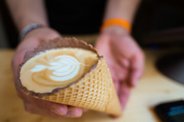 Barista handing a cappuccino in a ice cream cone