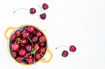 View from above on the bowl with fresh ripe red cherries on a white background. Summer berries, healthy food. Horizontal orientation, selective focus, copy space.