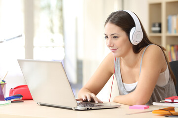 Student elearning on laptop with headphones at home