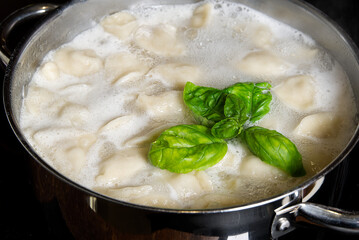 cooking dumplings in a pan with water, Meat in dough rolls. Top view.