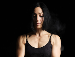 Naklejka premium adult woman with black hair dressed in a black sports top, looks down with a sad face