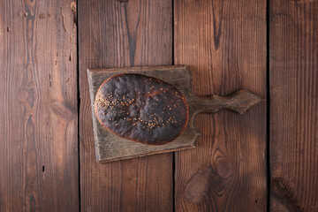 baked rye bread lies flour on a wooden old table, brown background