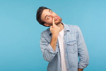 Misconduct, bad manners. Portrait of funny crazy man in worker denim shirt picking nose and...