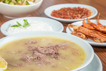 Turkish Traditional Soup with bread on white rustic wooden background, kelle, paca corbasi.