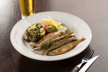 Seafood deep fried fish served with baked potato and beer on wooden table