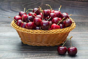 Ripe cherries in a wicker basket on a wooden background