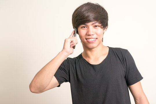 Portrait of happy young Filipino man talking on the phone