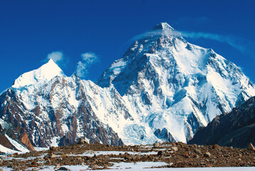 Snow peaks of mountains with Chogori K2 with blue sky. Winter tourism in Karakorum, Pakistan. Snow valley on horisontal landscape.