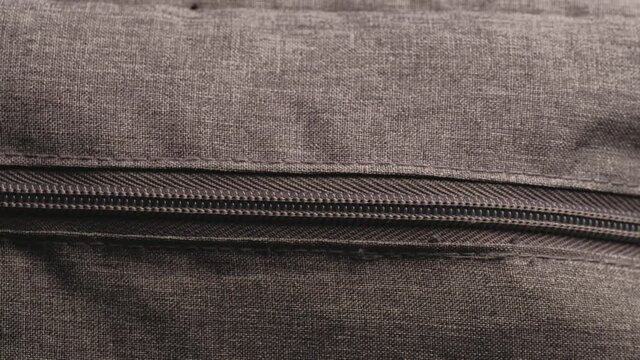 close and open zipper with metal slider body with leather pull tab of gray cloth bag by hand in low light mood.