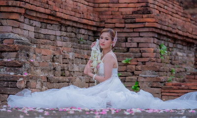 Thai young women portrait in Thai traditional dress at old temple, there is a garland in here hand, Chiangmai Thailand