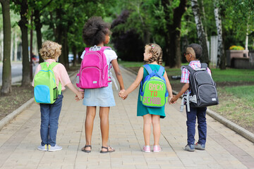 small schoolchildren with colorful school bags and backpacks run to school. Back to school, education, elementary school.